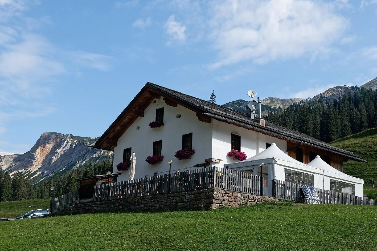 Malga Ra Stua, edificio bianco con tetto in legno tra i pascoli del Parco Naturale delle Dolomiti d'Ampezzo